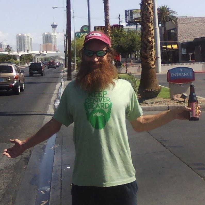 A man in a red cap holding a beer while wearing a green Keep Denver Beard T-shirt in Las Vegas